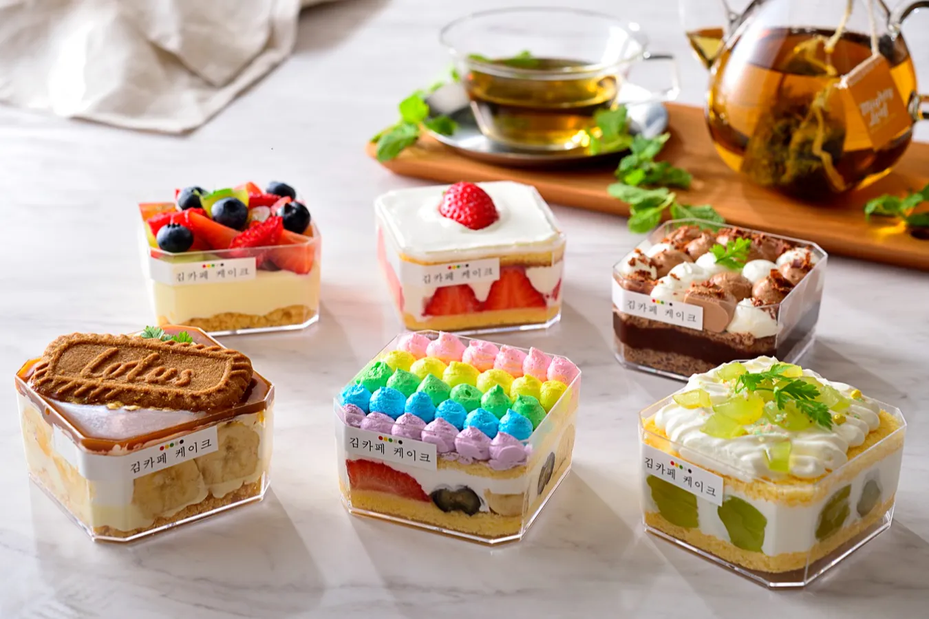 ▲「キューブケーキ」（各858円）。左上から時計まわりにフルーツレアチーズ、いちごショート、生チョコ、マスカット、Kimsレインボー、キャラメルバナナ