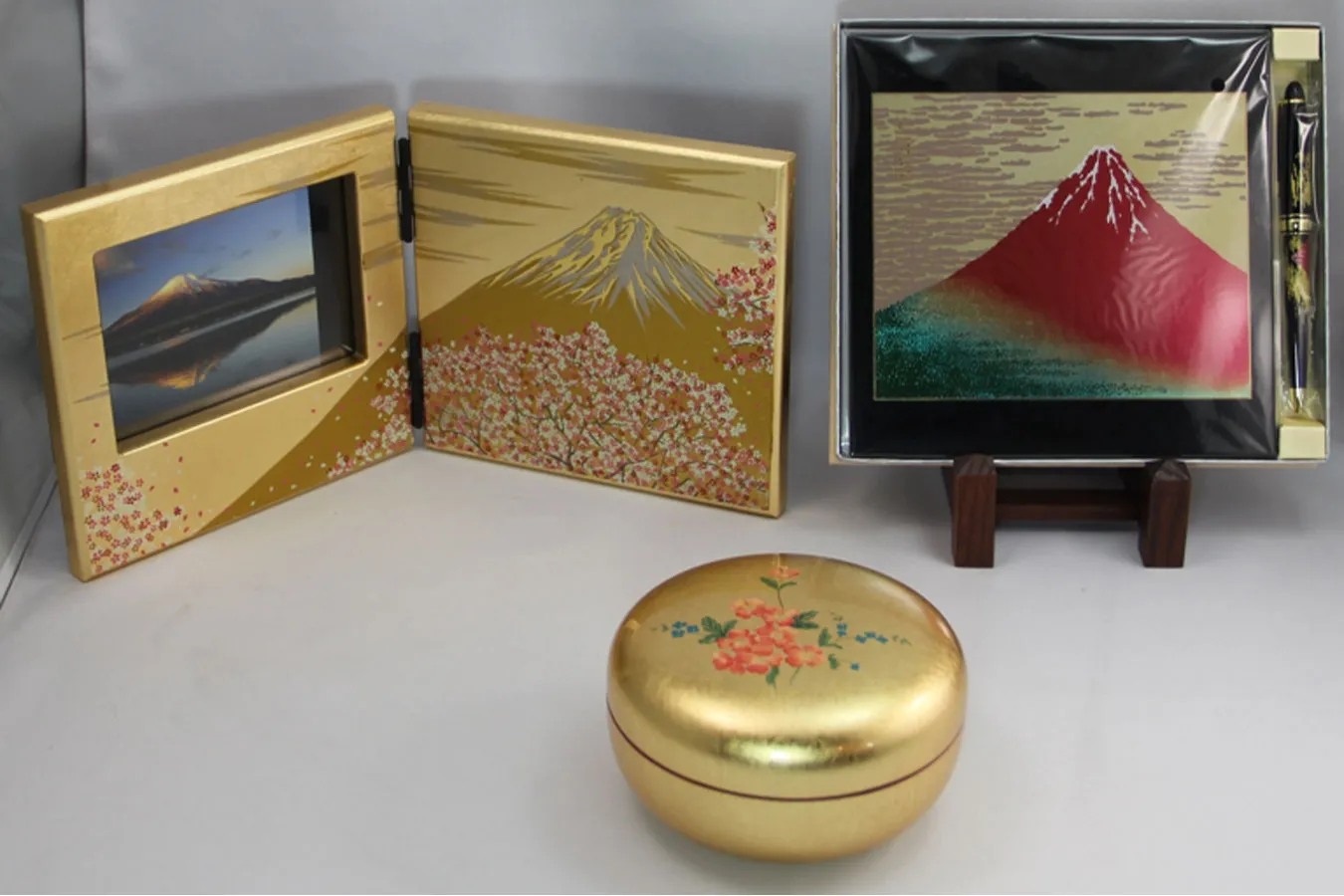 ▲「屏風時計富士雅桜小」（写真左6,050円）、「ボンボン入れ　はなみずき」（写真中央下3,190円）、「マウスパッド・ボールペンセット」（写真右4,400円）